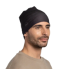 Una persona con barba viste un gorro oscuro como el Gorro Buff Niños Knitted y Polar Midy (copia) y un suéter beige, mirando hacia un lado contra un fondo blanco impoluto.