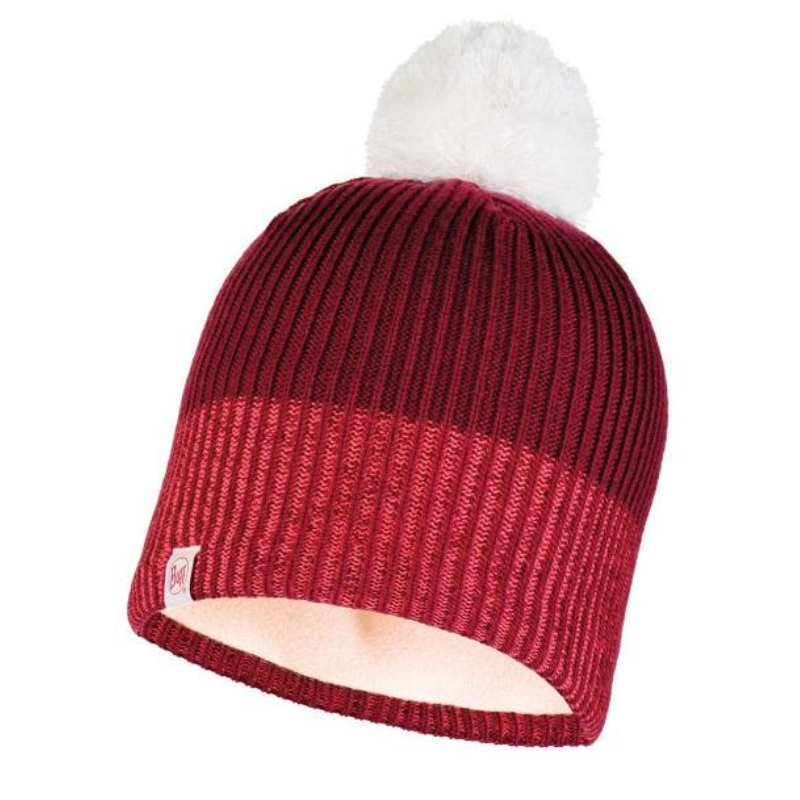 El Gorro Buff Niños Knitted y Polar Audny W es un gorro rojo y burdeos con un pompón blanco esponjoso y una pequeña etiqueta blanca en el borde delantero, que se muestra sobre un fondo blanco.