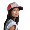 Con un mono blanco, una persona con una gorra de malla rosa con un estampado gráfico sonríe sutilmente a la cámara, transmitiendo un aire relajado al estilo Jockey Buff. El fondo sigue siendo blanco. Producto: Jockey Buff Trucker Green Campast (copia).