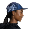 Una persona sonríe cálidamente con una gorra Jockey Buff Speed Pink Deri (copia) y una elegante chaqueta negra, con el pelo peinado sin esfuerzo en una cola de caballo baja. El fondo blanco liso realza su sencillez y encanto, y añade velocidad y gracia que recuerdan a un jockey.