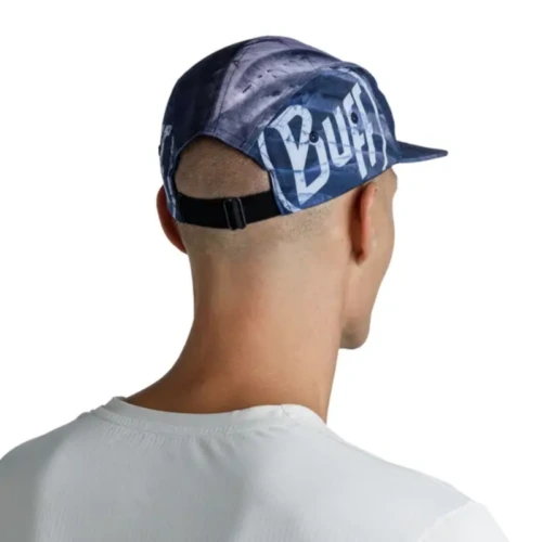 Se ve desde atrás a una persona que lleva una gorra Jockey Buff Speed Pink Deri con correa ajustable. La gorra de estilo deportivo, azul con patrones grises y la palabra "Buff" en el costado, se combina con una camisa blanca para lograr un estilo complementario.