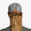 La vista posterior muestra a una persona con cabello rubio largo que fluye a través de una gorra de malla gris con tiras naranjas, con un estilo sencillo como el de Shane. Su camisa gris realza el estilo deportivo del conjunto Jockey Buff Speed Lilac Shane (copia).