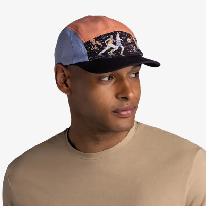 Un hombre que viste una gorra Jockey Buff Speed Ethnos Flame con patrones de inspiración étnica con bloques de colores y una camisa beige mira hacia un lado sobre un fondo liso.