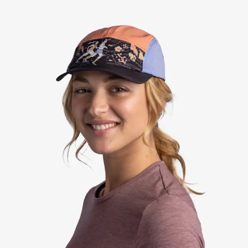 Una persona sonriente, con la gorra Jockey Buff Speed Ethnos Flame con un patrón gráfico, posa con una camisa granate sobre un fondo blanco, mostrando la vibrante energía del festival.