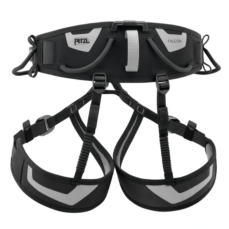 Arnés de escalada negro y gris con correas ajustables, cinturón ancho y dos perneras, diseñado para escalada y rápel seguros. La marca "Petzl" y el modelo "Falcon" son visibles en el cinturón.