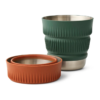 Dos tazas plegables Sea To Summit Detour: una naranja, plegada, y la otra verde oscuro, expandida. Ambas tienen exteriores de silicona acanalada y bordes de acero inoxidable.