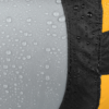 Primer plano de la tela impermeable y húmeda de la Bolsa de Compresión Sea To Summit Evac Compression UL, con gotas sobre una superficie texturizada gris y negra. La tela incluye un distintivo borde amarillo en el lado derecho, que resalta su durabilidad y estilo.