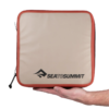 Una mano sostiene un estuche cuadrado beige y rojo con cremallera. El logo "Sea to Summit" se muestra audazmente en negro en la parte frontal, lo que sugiere su diseño robusto. Este cubo de embalaje hidráulico es perfecto para tus aventuras más exigentes.