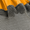 Un primer plano de una tela de malla negra texturizada, que se asemeja al tejido fino de un conjunto de bolsas secas (copia) de Sea to Summit Lightweight, envuelto sobre un material amarillo vibrante, crea un contraste sorprendente con la superficie lisa y brillante que se encuentra debajo.