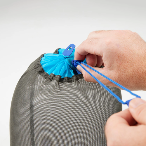 Primer plano de unas manos apretando el cordón azul de una bolsa de malla gris del Set de Bolsas Secas Ligeras Sea To Summit (copia), con el cordón enhebrado a través de un ajustador de plástico azul. El fondo es blanco liso.