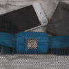 Un smartphone, una tableta y una hebilla de cinturón azul se ven parcialmente tras la malla hexagonal del set de bolsas secas Sea To Summit Lightweight (copia). El estampado oculta partes de los dispositivos, mientras que la hebilla azul resalta sobre sus tonos neutros.