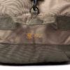 Primer plano de una mochila color caqui con un parche con el emblema de la Ruta 78 y el texto "70 LT" en amarillo. La tela tiene costuras visibles y un asa de red sobre el parche.