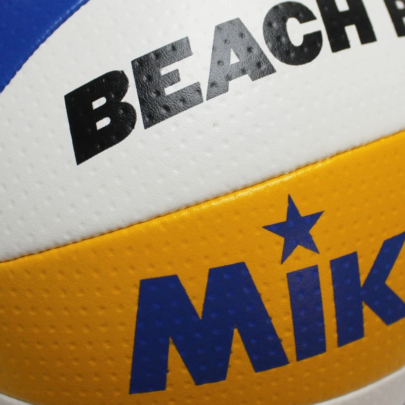 Primer plano de un Balón Playa Voleibol MIKASA BV550C que muestra partes de las palabras "BEACH" y "MIK" en sus paneles texturizados de color blanco, amarillo y azul.
