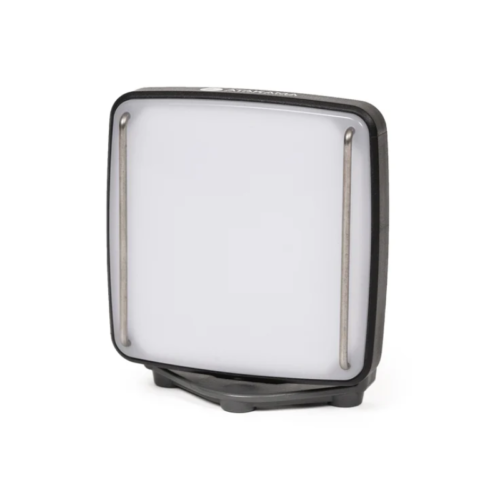 Una luz LED portátil cuadrada con un panel frontal blanco y una carcasa negra, colocada sobre un soporte pequeño y sencillo.