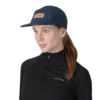Una persona con una camisa negra de manga larga y una gorra Jockey Atakama Outdoor Five Panel Puelo destaca sobre el fondo blanco liso. Lleva el cabello recogido en una coleta, lista para cualquier aventura al aire libre.