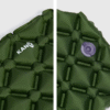 Primer plano de la Colchoneta Inflable Mat Yerba Loca Kano verde con patrón acolchado, logotipo "KANO" blanco a la izquierda y válvula de aire a la derecha, ideal para la comodidad al acampar.