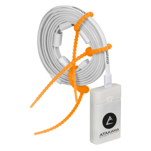 Un cable blanco enrollado asegurado con bridas de color naranja se conecta a un pequeño rectángulo con la etiqueta "Lámpara Led Line Atakama Outdoor Cruz del Sur 750lm", que presenta un logotipo de triángulo negro sobre un fondo blanco prístino, que se integra perfectamente con su entorno.