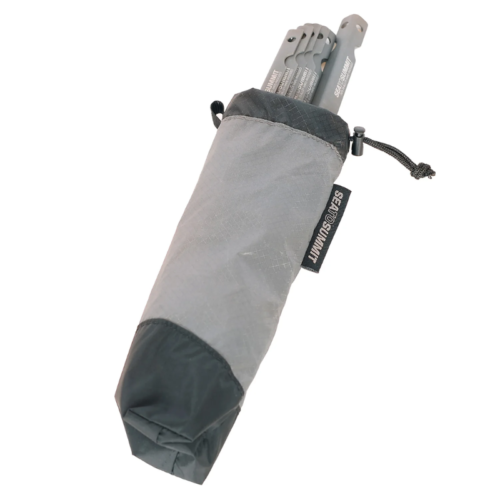 La bolsa para acampar Sea To Summit Ultra-Sil para carpas y utensilios de color gris y negro está parcialmente abierta para mostrar los postes de metal de la carpa doblados en el interior y presenta una etiqueta lateral con el icónico logotipo "Sea to Summit".