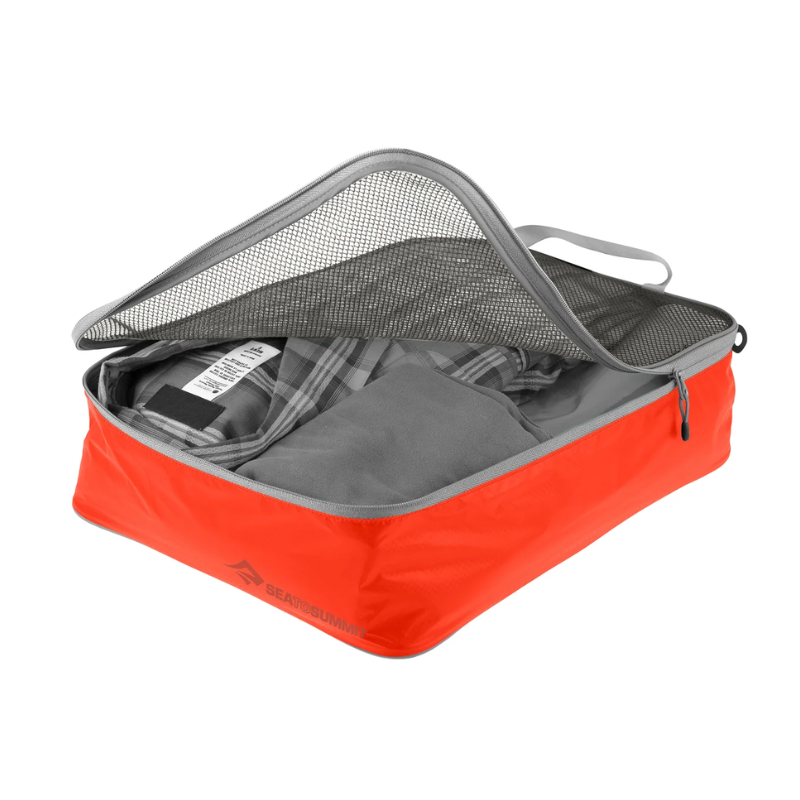 Una bolsa organizadora de malla para ropa Sea To Summit Bolsa Organizadora en color rojo está parcialmente abierta y muestra ropa cuidadosamente doblada a través de su tapa de malla negra, con el logotipo de la marca claramente visible en el costado.