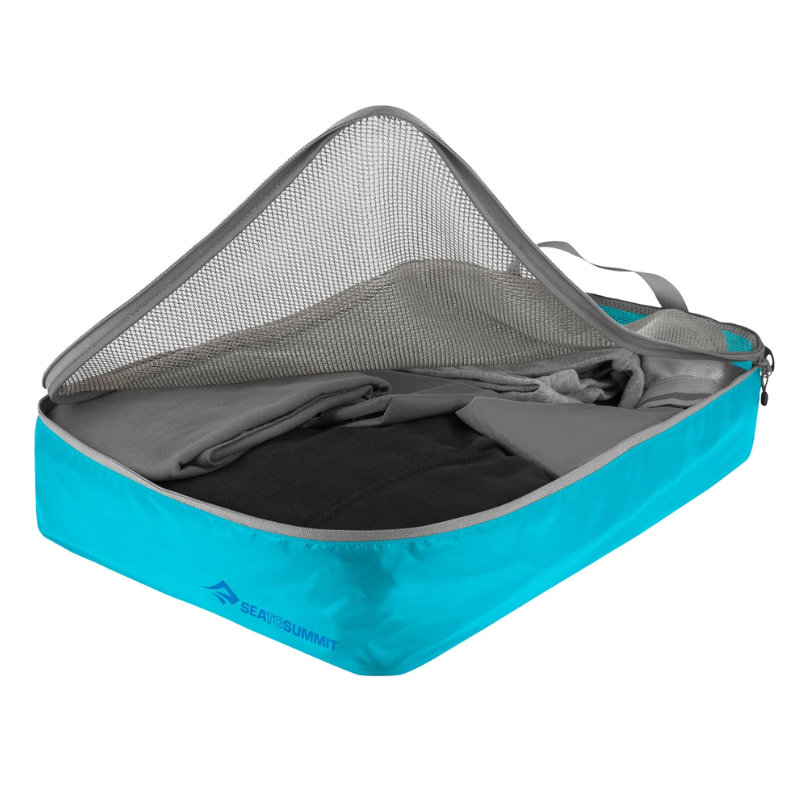 La Bolsa Organizadora de Ropa Sea to Summit turquesa está parcialmente abierta, revelando ropa cuidadosamente doblada en su interior. Presenta un panel de malla en la mitad superior y un asa gris en un lateral, con el logotipo de la marca en la parte frontal.